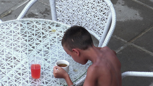 坐在餐桌边的可爱小可爱男孩喝果汁和茶做早餐健康生活29秒视频