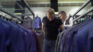 购物和时装概念青年男子在商场选择和试穿夹克15秒视频