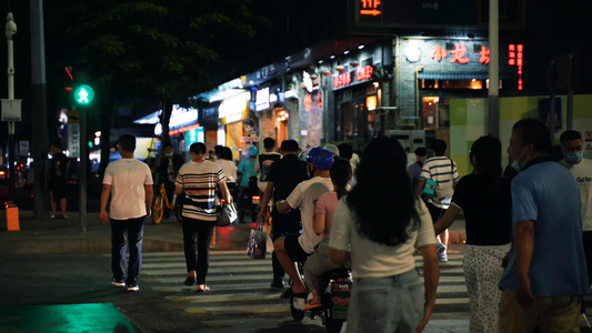 城市夜晚马路上过红绿灯的行人[变灯]视频