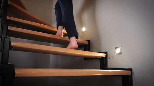 赤脚女性双腿走在木制现代室内木制门式室内楼梯上视频