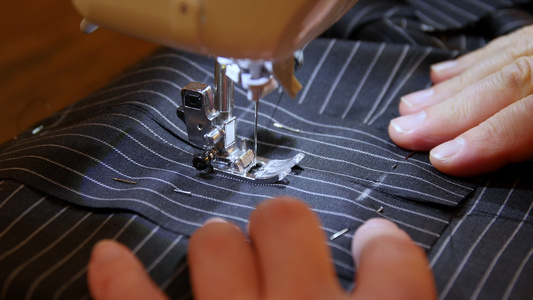 女裁缝在缝纫机上缝制黑色条纹布制成的衣服通过内置硬件视频