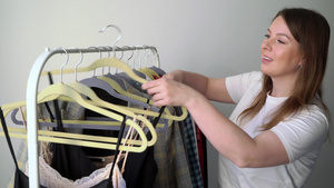 年轻妇女在衣架上选择衣服寻找应穿的衣服商店或衣柜16秒视频