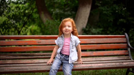 可爱的小女孩坐在长椅上视频