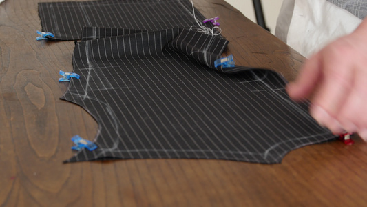 一个裁缝的手用麻线缝制一件高级意大利剪裁羊毛面料的视频