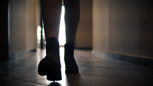 穿着靴子的女子匆忙走近摄像头沿着狭窄的黑暗通道走廊16秒视频