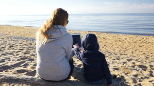 母亲和儿子在海滩上用平板电脑11秒视频