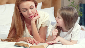 美丽的女人和可爱的小女儿一起看书躺在家里的床上睡着12秒视频