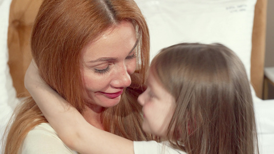 快乐的母亲拥抱她的小女儿拥抱对着镜头微笑视频