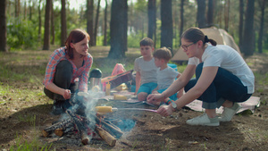 两位母亲在夏季家庭野营度假期间在森林里的帐篷里煮香肠15秒视频