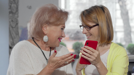 成年女人在她的智能手机上向年长母亲展示一些东西视频