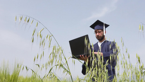 一个人在田野毕业的男人看笔记本电脑扔蓝色帽子虚拟毕业40秒视频