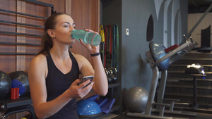 运动女学生在休息时看电话和喝水12秒视频