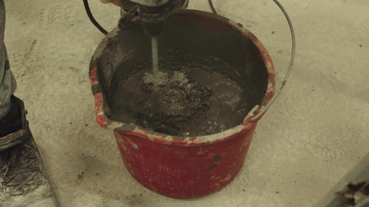将水泥迫击炮混入一个装有搅拌器的桶里视频