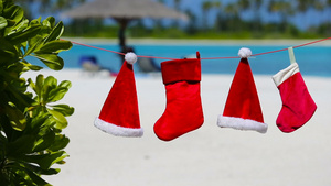 热带海滩上挂着红色圣塔帽和圣诞长袜10秒视频