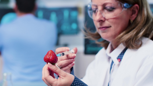 女性研究人员将Gmog注射到草莓中的静近镜头视频