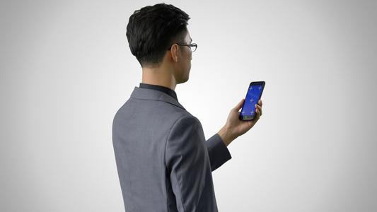 4k灰底抠像合成商务男性使用蓝幕手机背影视频