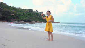 一个穿着黄色裙子的年轻美女在海边自拍9秒视频