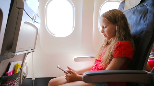 可爱的小女孩乘飞机旅行坐在飞机窗口附近的孩子听音乐视频