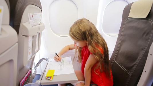 可爱的小女孩乘飞机旅行孩子用坐在飞机窗边的彩色铅笔画视频