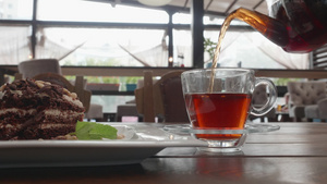 从咖啡桌上的透明茶壶中将浓郁的茶倒入玻璃杯中夏季咖啡馆16秒视频