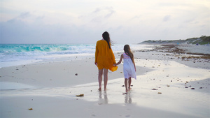 可爱的小女孩和年轻母亲在温暖的夜晚在热带海滩上14秒视频