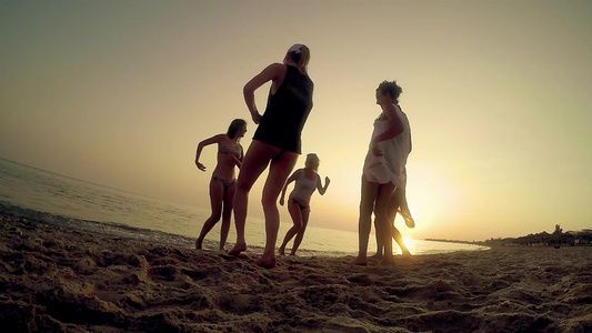 5名穿比基尼的女子在夏日海滩日落时慢动作跳舞视频