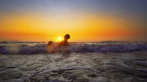 年轻微笑的女士坐在海浪中在日落暑假时放松28秒视频
