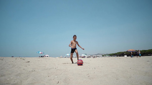 沙滩上的小男孩玩足球足球球慢动作运动30秒视频