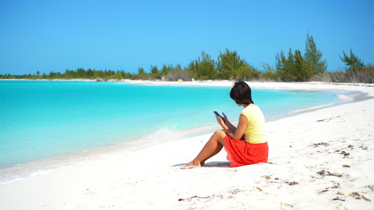 在热带海滩度假期间青年女子带着手机旅游者使用移动智能手机视频