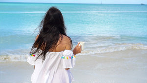 在白色热带沙滩上喝着热饮的年轻女子慢动作女孩享受美丽12秒视频