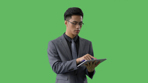 4k绿幕合成抠像穿西装戴眼镜的商务男士使用平板电脑上网17秒视频
