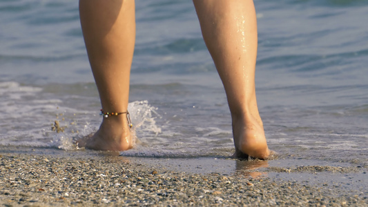 海滩旅行走在沙滩上的女人在沙滩上留下脚印女性脚和金沙视频