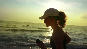 配有马尾和耳机训练的跑步女孩在夏日海滩日落时慢跑嗯19秒视频