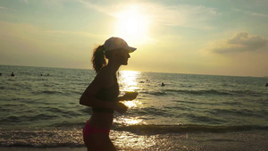 戴帽子的年轻运动女青年在日出日落时正在海上参加体操比赛11秒视频