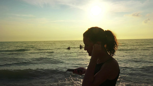穿着马尾和耳机的跑漂亮女孩在夏日海滩日落时放松慢跑24秒视频