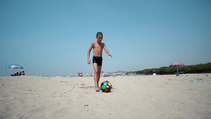 快乐的孩子踢足球赤脚跑在湿沙沙滩上踢球缓慢运动电影30秒视频