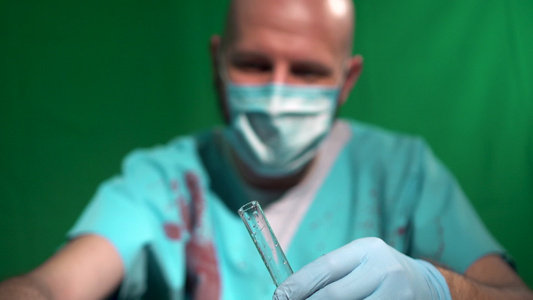 外科医生穿着覆盖着血液的面罩袍用吸管填充试管玻璃容器视频
