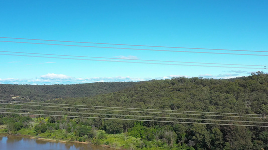 横跨一条河流的输电塔电力线的空中飞行录像视频