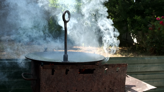 火烧烟熏的烤锅暖和起来在开着的火上煮饭视频