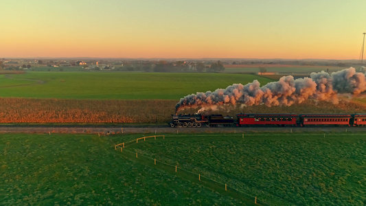 金色日出时蒸汽发动机和客车的空中风景满头蒸汽视频