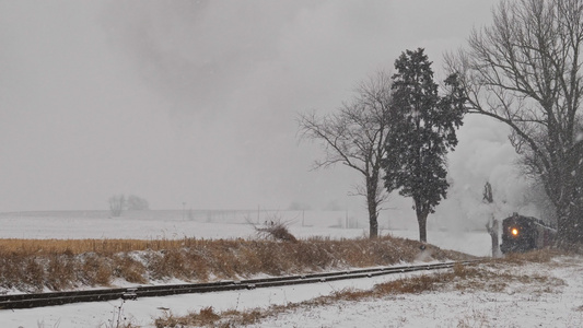 古董修复机车和客运教练在暴风雪中接近的视频