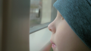 坐在火车上一个戴着帽子的小男孩看着窗外22秒视频