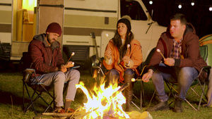 朋友们在露营的火炉周围放轻松用棍子烤棉花糖10秒视频