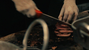 双手紧握在砧板上的烟熏牛腩迅速将煮熟的牛肉切成薄片10秒视频