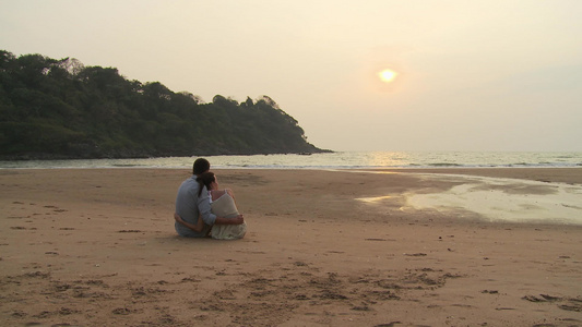 日落时坐在沙滩上的情侣视频