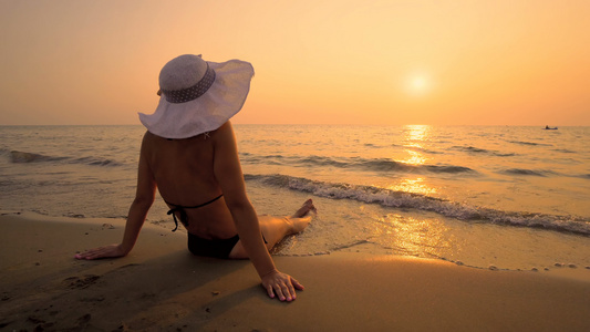 有帽子的性感女人享受热带沙滩日落和海浪喷溅视频