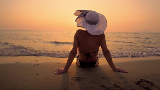 有帽子的性感女人享受热带沙滩日落和海浪喷溅视频