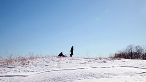 母亲带着两个孩子在雪地里拉着雪橇15秒视频