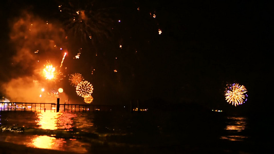 明亮的金烟花在海面上空的夜空中爆炸视频