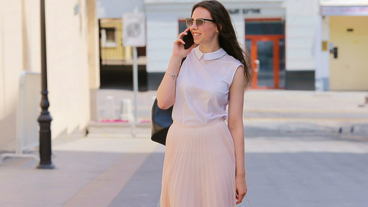 年轻的白种女孩在欧洲城市用她的智能手机在户外说话街上视频